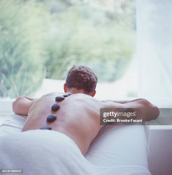 man having hot stone therapy - マッサージ台 ストックフォトと画像