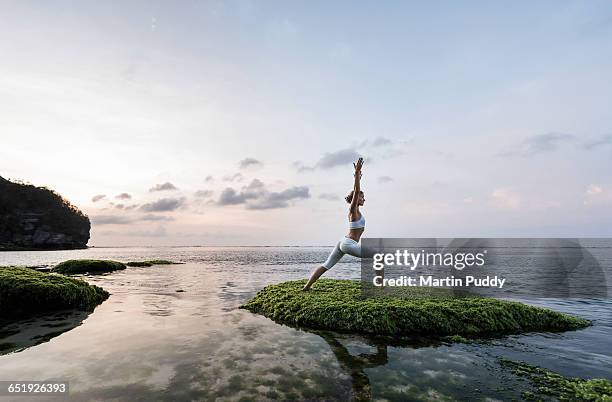 young woman practicing yoga on seashore - yoga outdoor foto e immagini stock