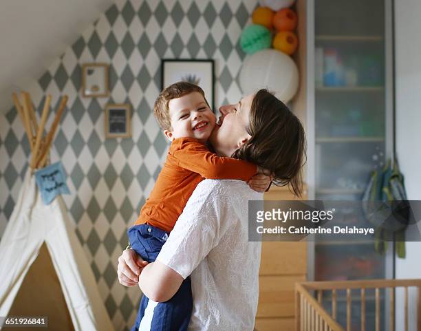 a mom with her son in her arms - stringere foto e immagini stock