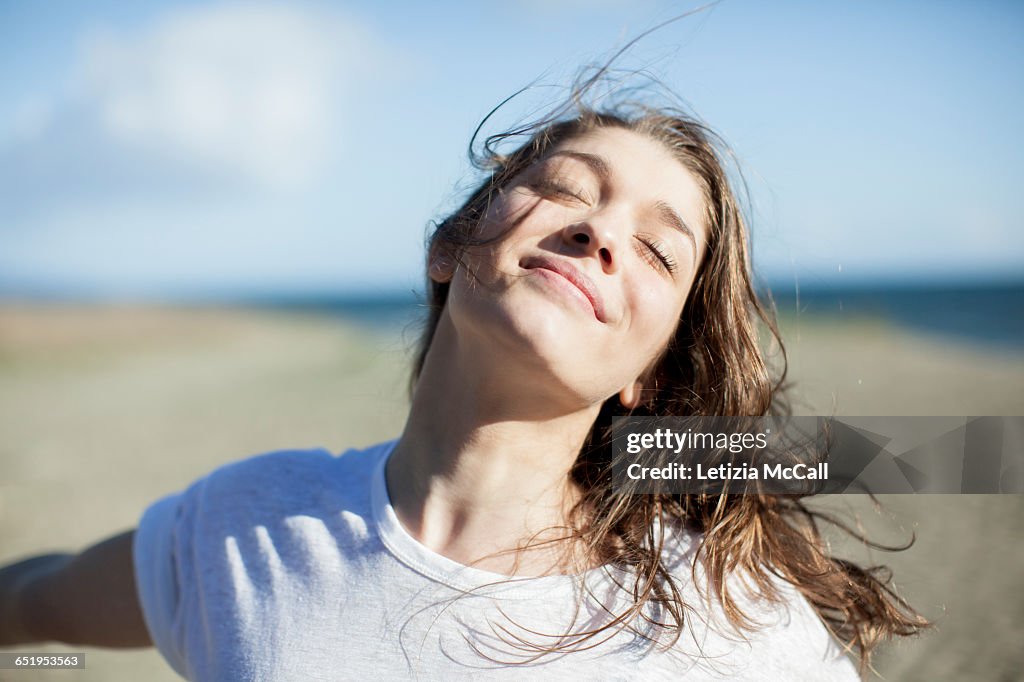 Young woman with eyes closed smiling on a beach