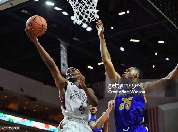 Ian Baker of the New Mexico State Aggies drives in for a layup against Broderick Newbill of the UKMC Kangaroos during a semifinal game of the Western...