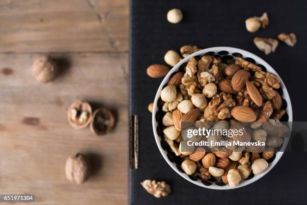 walnuts, almonds and hazelnuts in a bowl on black background - ナッツ類 ストックフォトと画像