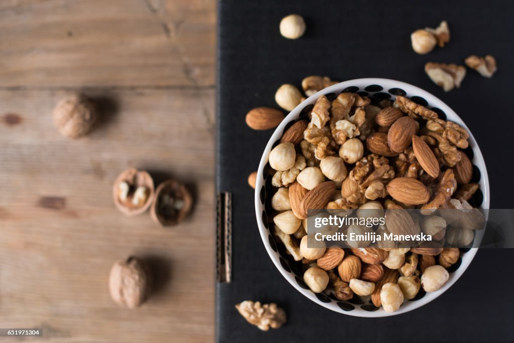 Walnuts, almonds and hazelnuts in a bowl on black background