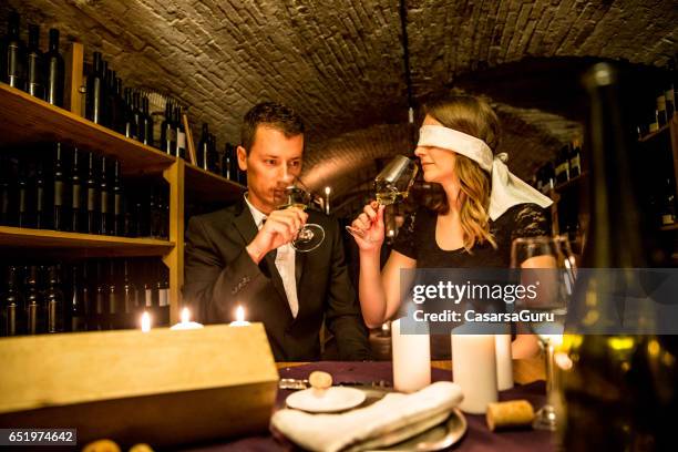 giovane coppia in cantinatasting wine blindfold - degustazione di vino foto e immagini stock