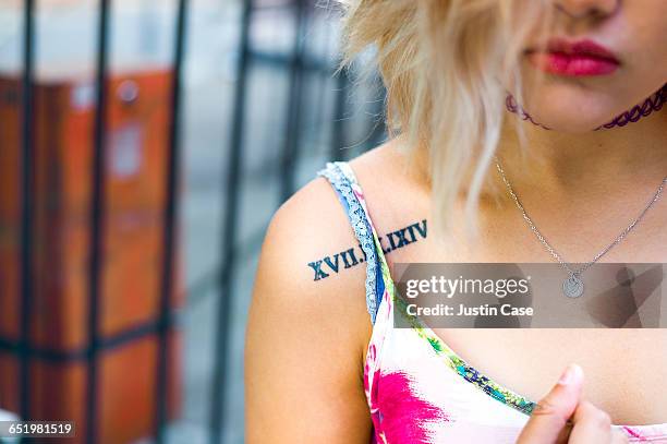 woman with red lips showing tattoo on shoulder - römische zahl stock-fotos und bilder