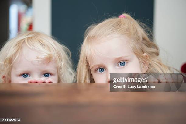 two sisters looking just above the table - fotohandy stock pictures, royalty-free photos & images