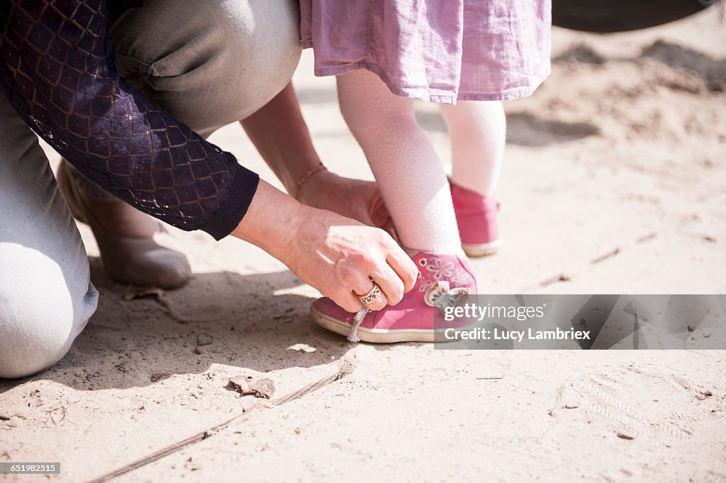 Mother tying her daughter's shoe laces