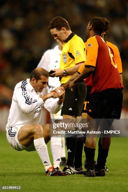 Real Madrid's Zinedine Zidane is helped up by AS Roma's Aldair as referee Hugh Dallas prepares to book him