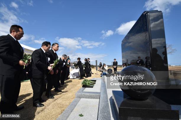 People offer flowers at the monument of the victim of the 2011 quake-tsunami disaster during a memorial service in Namie, a no entry zone in...