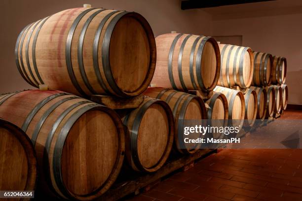 row of barrels emerging from darkness in a wine cellar - barrels ストックフォトと画像