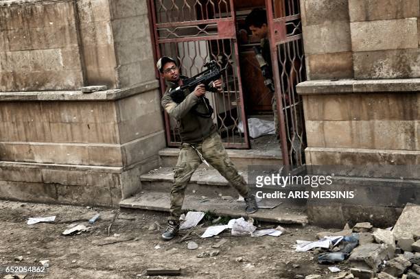 Iraqi forces members fire from outside the museum towards Islamic State jihadists' positions in west Mosul on March 11, 2017 during the ongoing...