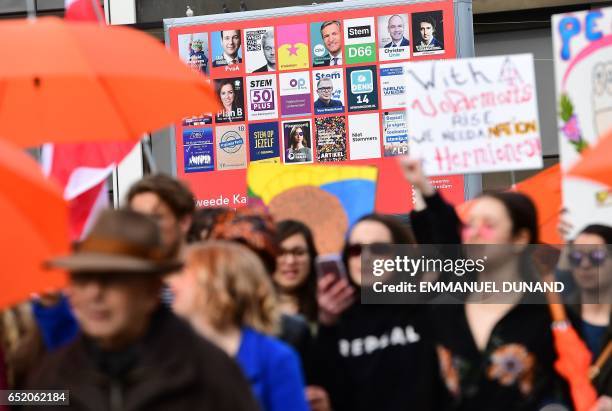 People walk by electoral posters while taking part in the anti-racism demonstration called "Womens march for a united Netherlands" ahead of the Dutch...