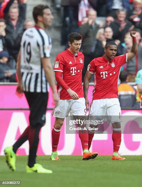 Douglas Costa of FC Bayern Muenchen celebrates his first goal with teammate Robert Lewandowski as David Abraham of Eintracht Frankfurt reacts during...