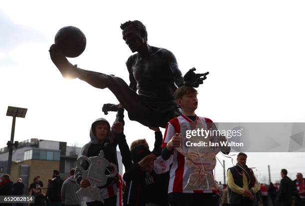 Fans pose with the Dennis Bergkamp statue outside the stadium prior to The Emirates FA Cup Quarter-Final match between Arsenal and Lincoln City at...