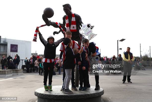 Fans pose with the Dennis Bergkamp statue outside the stadium prior to The Emirates FA Cup Quarter-Final match between Arsenal and Lincoln City at...