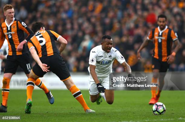 Harry Maguire of Hull City tackles Jordan Ayew of Swansea City during the Premier League match between Hull City and Swansea City at KCOM Stadium on...