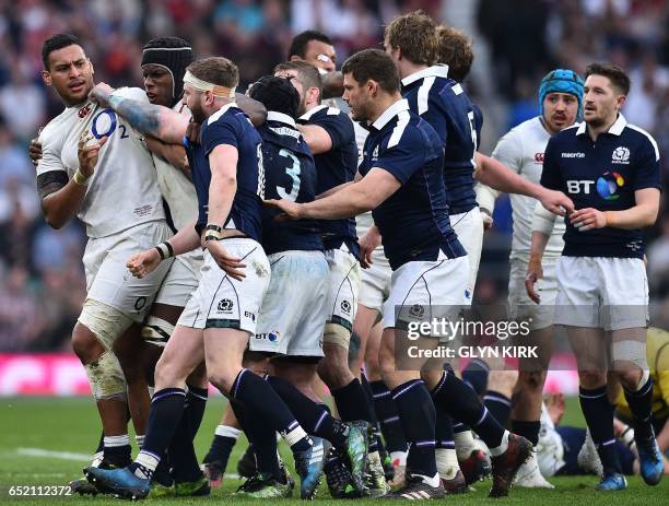 England's number 8 Nathan Hughes remonstrates Scotland's fly-half Finn Russell and Scotland's prop Zander Fagerson with following his tackle on...