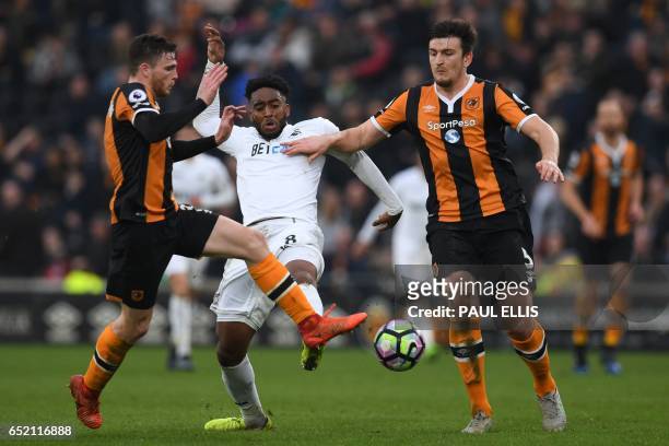 Swansea City's Dutch midfielder Leroy Fer vies with Hull City's Scottish defender Andrew Robertson and Hull City's English defender Harry Maguire...