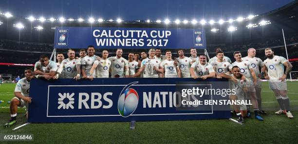 England's hooker and captain Dylan Hartley holds the Calcutta Cup trophy as he poses with teammates atfter winning the Six Nations international...