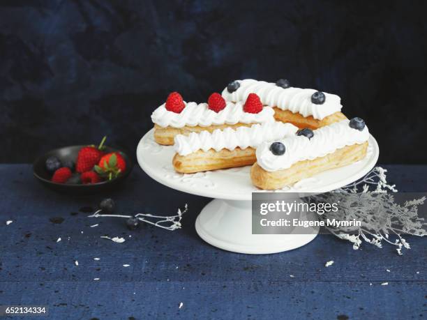 eclairs with whipped cream and berries - relámpago de crema fotografías e imágenes de stock