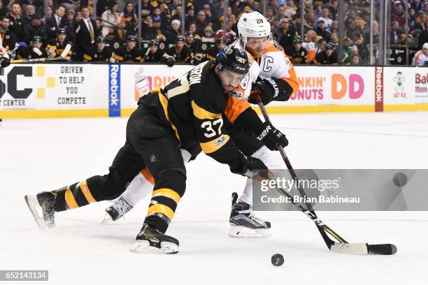 Patrice Bergeron of the Boston Bruins fights for the puck against Claude Giroux of the Philadelphia Flyers at the TD Garden on March 11, 2017 in...