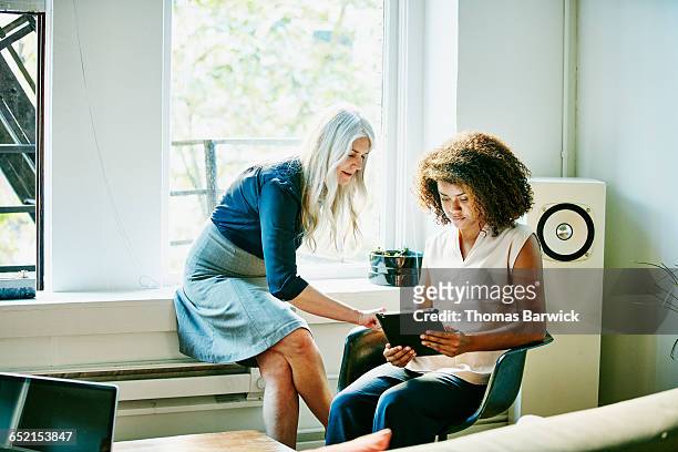 businesswomen discussing project on digital tablet - supportive coworker stock pictures, royalty-free photos & images