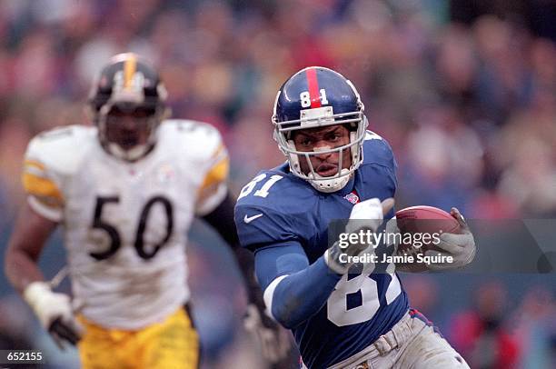 Amani Toomer of the New York Giants runs with the ball against Earl Holmes of the Pittsburgh Steelers during the game at the Giants Stadium in East...
