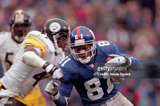 Amani Toomer of the New York Giants iruns with the ball against Lee Flowers of the Pittsburgh Steelers during the game at the Giants Stadium in East...