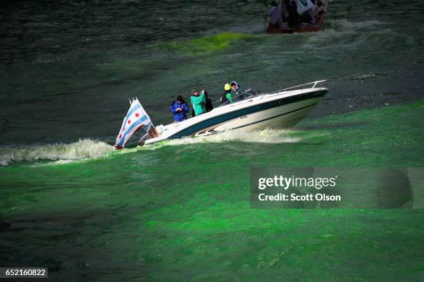 Workers use a boat to mix dye into the Chicago River to turn it green in celebration of St. Patrick's Day on March 11, 2017 in Chicago, Illinois....