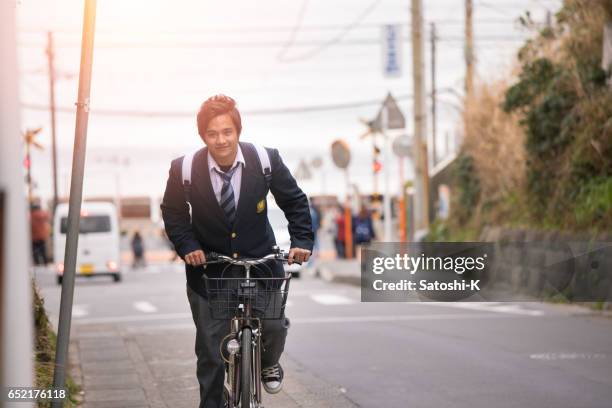 斜面高校少年乗馬自転車 - 制服 ストックフォトと画像