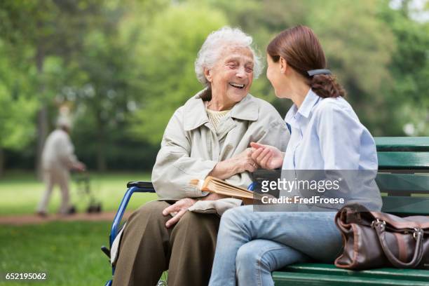 senior woman with caregiver in the park - care stock pictures, royalty-free photos & images