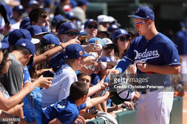 Joc Pederson of the Los Angeles Dodgers signs autographs before the MLB spring training game against the Los Angeles Angels at Camelback Ranch on...
