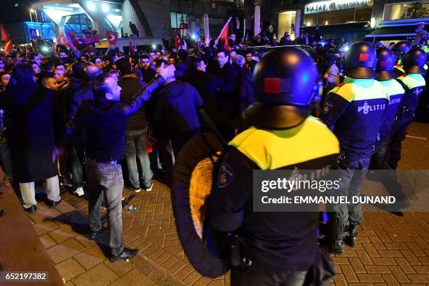 Police officers face Turkish residents of the Netherlands gathered for a protest outside Turkey's consulate in Rotterdam on March 11, 2017. Protests...