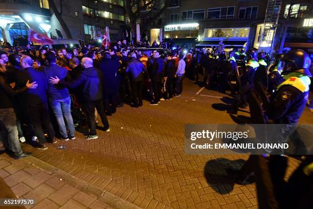 Police officers face Turkish residents of the Netherlands gathered for a protest outside Turkey's consulate in Rotterdam on March 11, 2017. Protests...