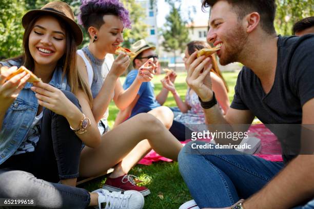 friends eating pizza outside - university student picnic stock pictures, royalty-free photos & images