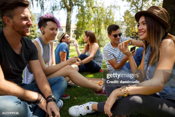 friends eating pizza outside - university student picnic stock pictures, royalty-free photos & images