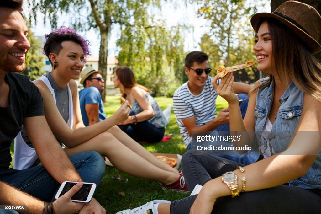 Friends eating pizza outside