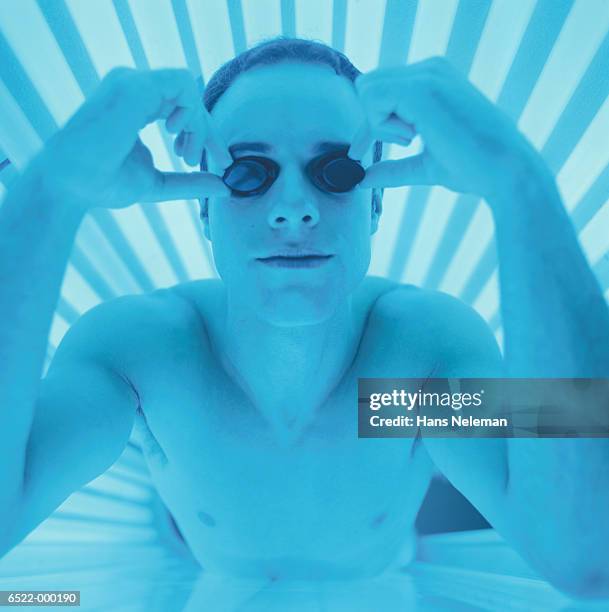 man on tanning bed - zonnebank stockfoto's en -beelden