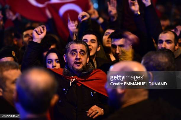 People gesture and wave flags as Turkish residents of the Netherlands gather for a protest outside Turkey's consulate in Rotterdam on March 11, 2017....
