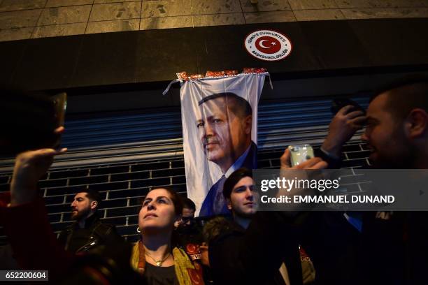 People pose for 'selfies' in front of a flag bearing a portrait of Turkish President Recep Tayyip Erdogan as Turkish residents of the Netherlands...