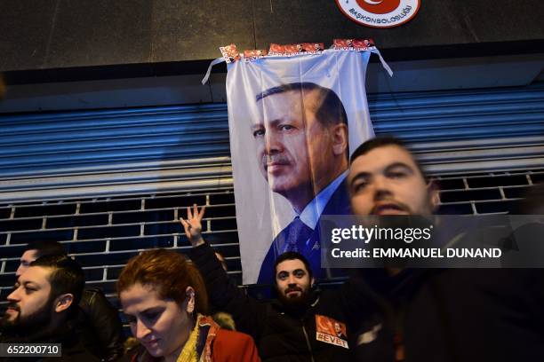 Man gestures in front of a flag bearing a portrait of Turkish President Recep Tayyip Erdogan as Turkish residents of the Netherlands gather for a...