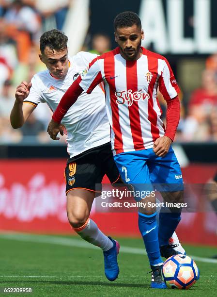 Munir El Haddadi of Valencia competes for the ball with Douglas Pereira of Real Sporting de Gijon during the La Liga match between Valencia CF and...