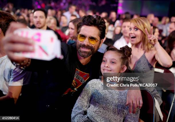 Actor John Stamos takes a selfie with a fan while actor Candace Cameron Bure photobombs at Nickelodeon's 2017 Kids' Choice Awards at USC Galen Center...