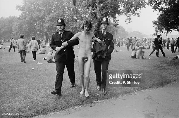 Naked man being escorted away by police at the Hyde Park music festival, London, UK, 3rd July 1971.