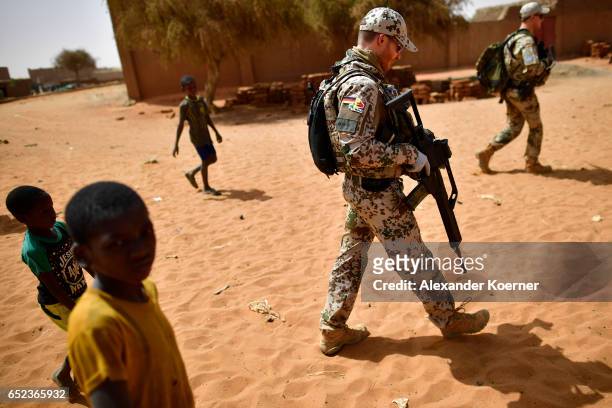 Children follow soldiers of the Bundeswehr, the German Armed Forces, after leaving a weekly cattle market on the outskirts of Gao on March 7, 2017 in...