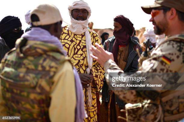 Local farmers talk to soldiers of the Bundeswehr, the German Armed Forces, during a weekly cattle market on the outskirts of Gao on March 7, 2017 in...