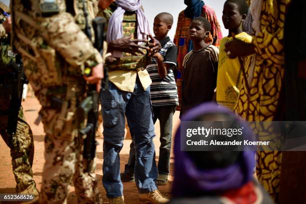 Children wach soldiers of the Bundeswehr, the German Armed Forces, while visiting a weekly cattle market on the outskirts of Gao on March 7, 2017 in...