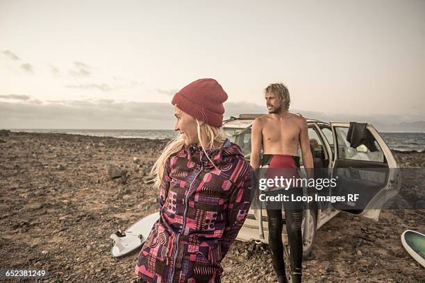 a couple look across the beach at corralejo in fuerteventura - wetsuit stock pictures, royalty-free photos & images