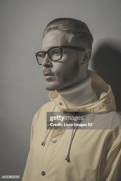 studio portrait of a bearded young man in a yellow wind cheater - cheater stock pictures, royalty-free photos & images