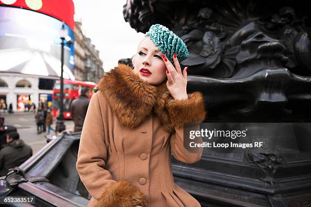 a stylish young woman dressed in 1930s style clothing standing by the statue of eros at piccadilly circus - 1930s woman stock pictures, royalty-free photos & images